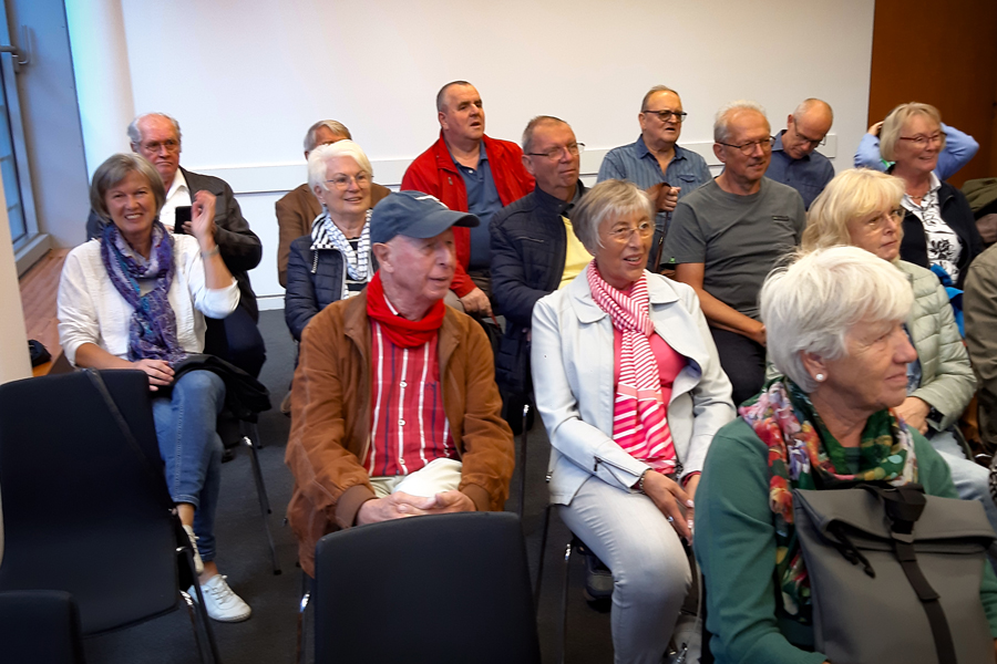 Personen sitzen in Reihen nebeneinander