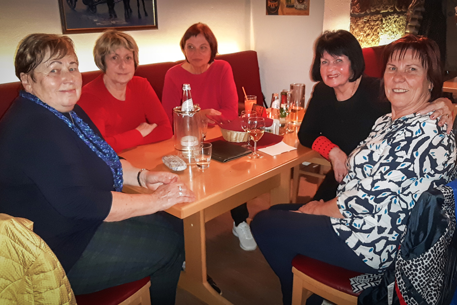 Frauen sitzen an einem Tisch und lächeln in die Kamera