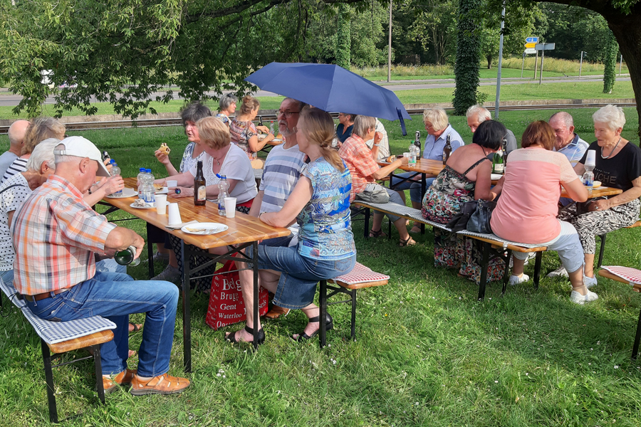 Personen sitzen auf Bierbänken und essen