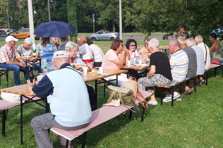 Personen sitzen auf Bierbänken und essen