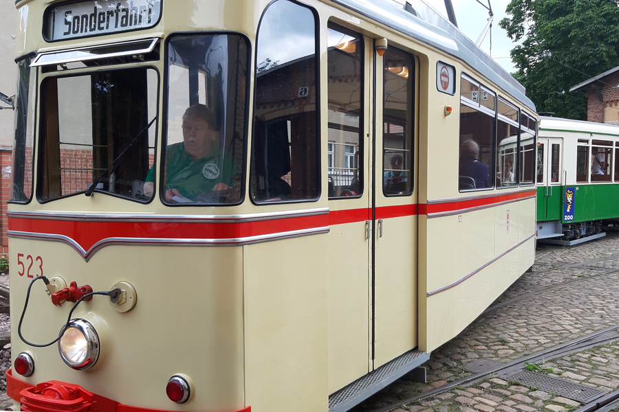 beigefarbene historische Straßenbahn mit Fahrer