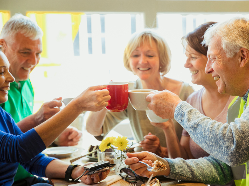 fünf Personen stoßen mit einer Kaffeetasse an